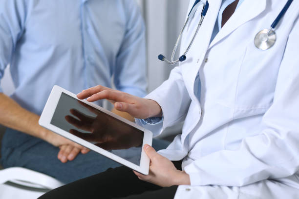 istock Female doctor using touchpad or tablet computer while consulting man patient in hospital. Medicine and healthcare concept 946948568