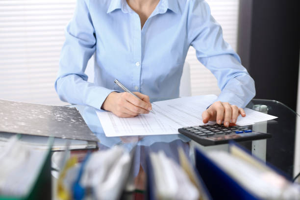 istock Female bookkeeper or financial inspector  making report, calculating or checking balance. Internal Revenue Service checking financial document. Audit concept in busines 946948834