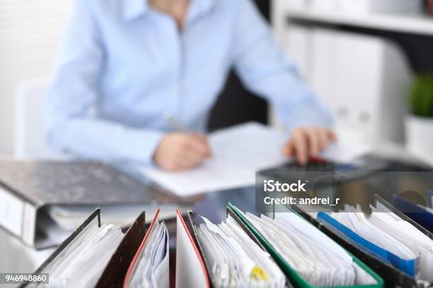 Binders With Papers Are Waiting To Be Processed With Businesswoman Or Secretary Back In Blur Stock Photo - Download Image Now