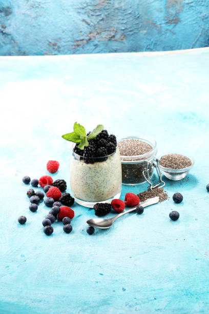 istock Healthy berry chia pudding in a jar with scattered fruit isolated on rustic grey background 946958254