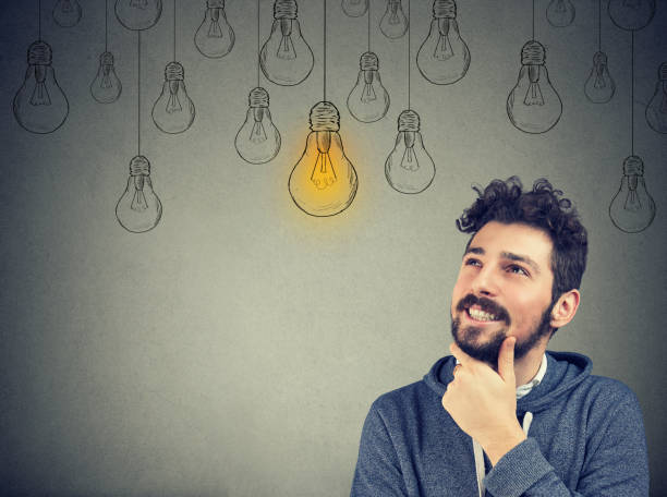 istock thinking man smiling looking up at light idea bulb above head 946964880
