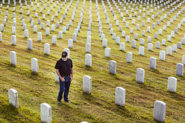 Authentic Vietnam Veteran Walking in Military Cemetary Bearded Vietnam veteran standing, pacing and walking in a United States military cemetery. soldier grave stock pictures, royalty-free photos & images