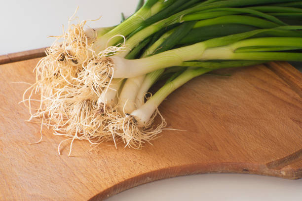 pile of spring onions on a cutting board stock photo