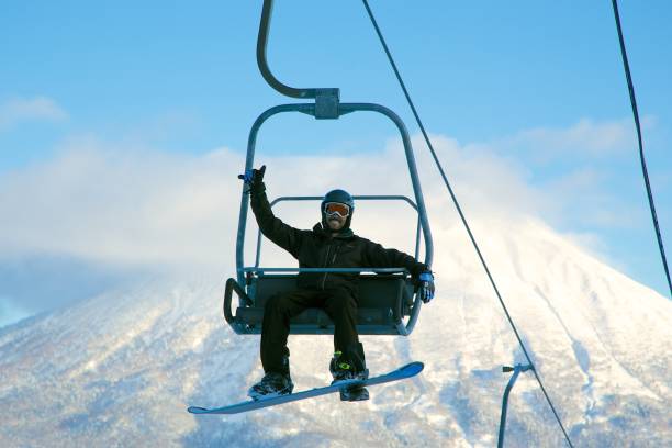 Ski lift in Niseko, Japan Snowboarder on a ski lift in Niseko, Japan japanese snowboarder stock pictures, royalty-free photos & images