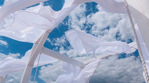 istock Sheds  awning with fabric white curtains on the seashore breeze in the wind 946987112
