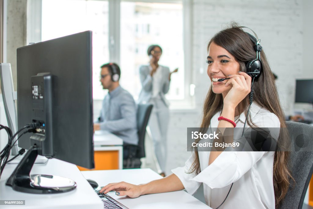 Young friendly operator woman agent with headsets working in a call centre. Call Center Stock Photo