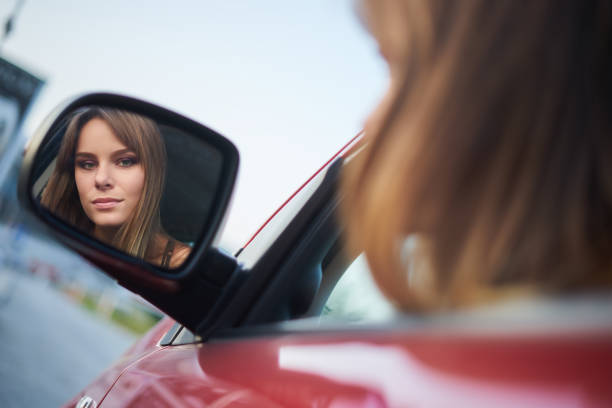 istock Beautiful girl sit in car looking in a mirror 947007442