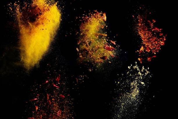 different spices thrown into the air against black background stock photo