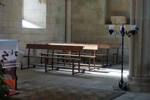 Empty church pews with a partial view of an altar and candles.