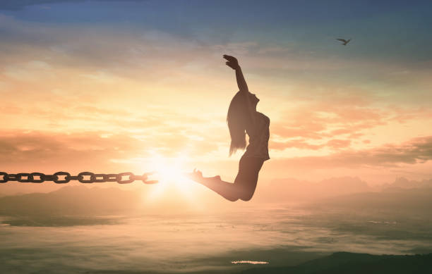 Freedom concept Silhouette of a girl jumping and broken chains at sunset meadow with her hands raised recovery photos stock pictures, royalty-free photos & images