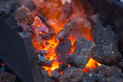 blacksmith furnace with burning coals, tools, and glowing hot metal workpieces