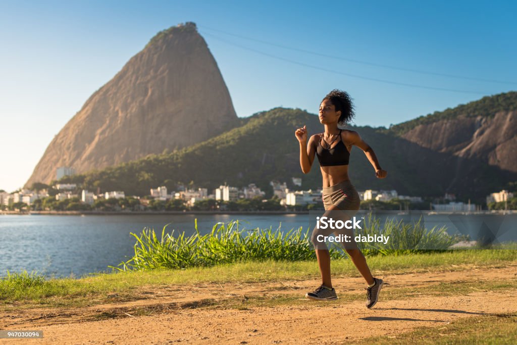 Donna fitness che corre su una strada sterrata - Foto stock royalty-free di Correre