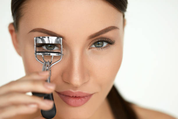 istock Beautiful Woman Using Eyelash Curler On Curly Long Eyelashes 947030598