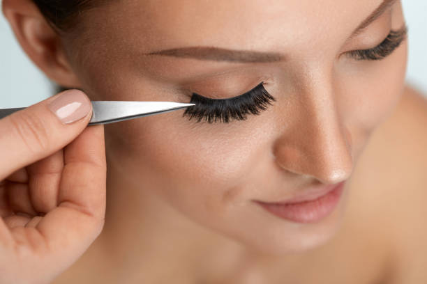 istock Beauty Makeup. Woman Applying Black False Eyelashes With Tweezer 947030718