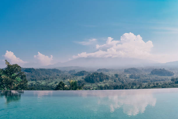 Asia travel series. swimming pool with stunning view on volcano Agung in Bali, covered by clouds on sunrise