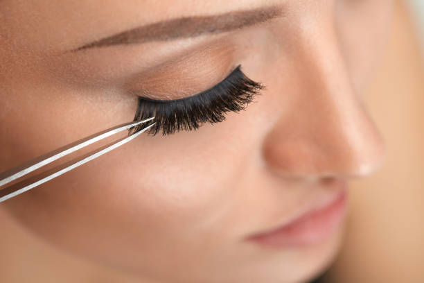 belleza maquillaje. mujer aplicación de pestañas postizas negro con pinza - applying make up flash fotografías e imágenes de stock