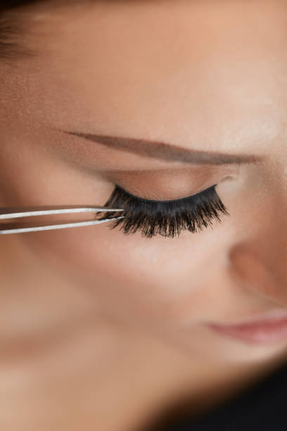 belleza maquillaje. mujer aplicación de pestañas postizas negro con pinza - applying make up flash fotografías e imágenes de stock