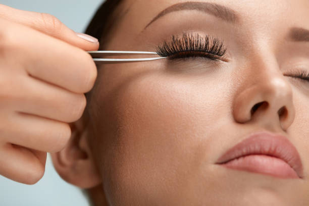 belleza maquillaje. mujer aplicación de pestañas postizas negro con pinza - applying make up flash fotografías e imágenes de stock