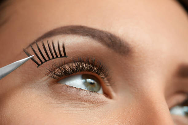 primer plano de bella mujer ojo con pestañas postizas negras largo - applying make up flash fotografías e imágenes de stock