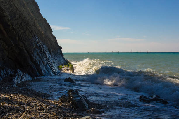 istock rocky sea shore with pebble beach, waves with foam 947033434