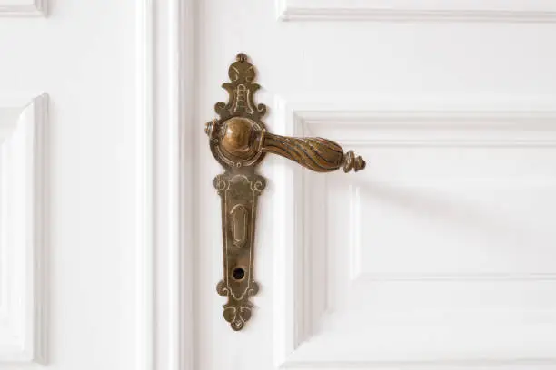 Photo of old door handle closeup on wooden door in beautiful apartment - interior