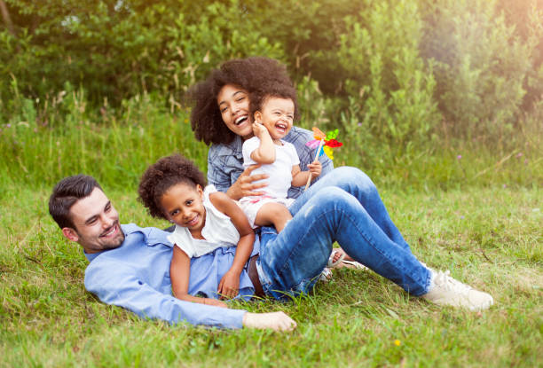счастливая семья на открытом воздухе в парке. - family grass toddler african descent стоковые фото и изображения