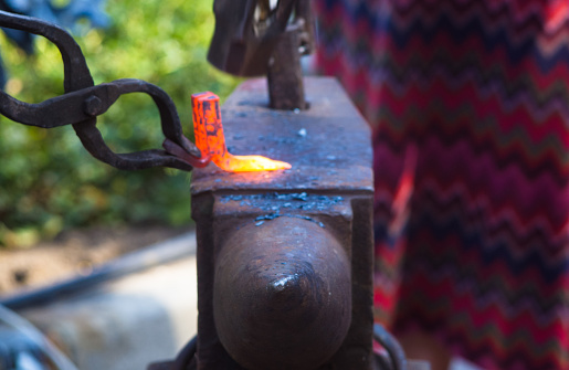 blacksmith performs the forging of hot glowing metal on the anvil