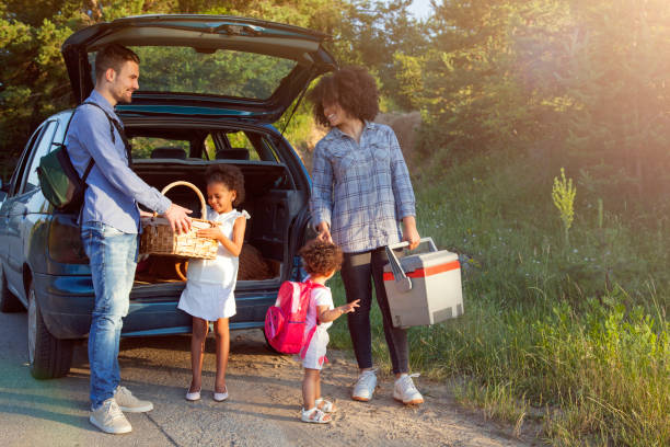 buona famiglia che scarica i bagagli dall'auto per le vacanze estive. - car family picnic vacations foto e immagini stock