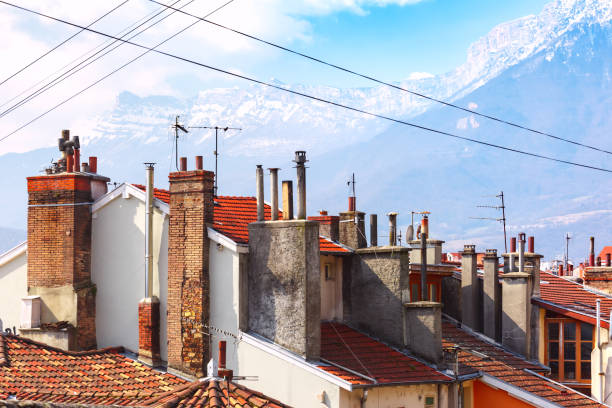 Tiled roofs with pipes Grenoble, France Typical French tiled roofs and chimney pipes in the background of the Alps mountains, Grenoble, France isere river stock pictures, royalty-free photos & images