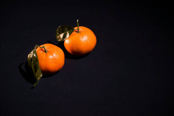 dos cítricos mandarina con cocimiento sobre fondo negro - leafes fruit orange leaf fotografías e imágenes de stock