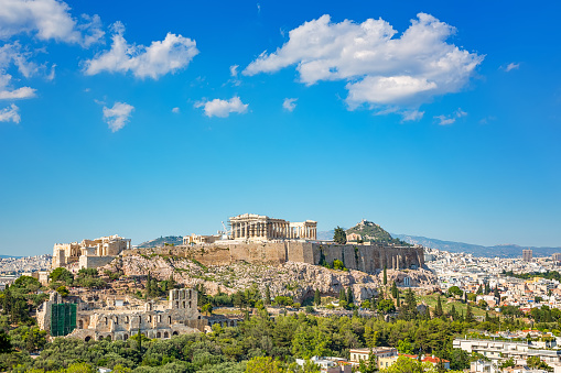 Behold the timeless majesty of the Acropolis, adorned with the Parthenon, Erechtheum, Beule Gate, and Temple of Athena, as viewed from the historic Areopagus Hill on rock in the heart of Athens. From this vantage point, ancient ruins tell stories of bygone civilizations against a backdrop of modern city life. The Parthenon stands as a symbol of classical architecture, while the Erechtheum's Caryatids captivate with their timeless grace. Beyond lies the Beule Gate and the Temple of Athena, each a testament to the city's rich cultural heritage. As the sun sets, casting a golden hue over the landscape, the Acropolis remains an enduring beacon of Athens' illustrious past.