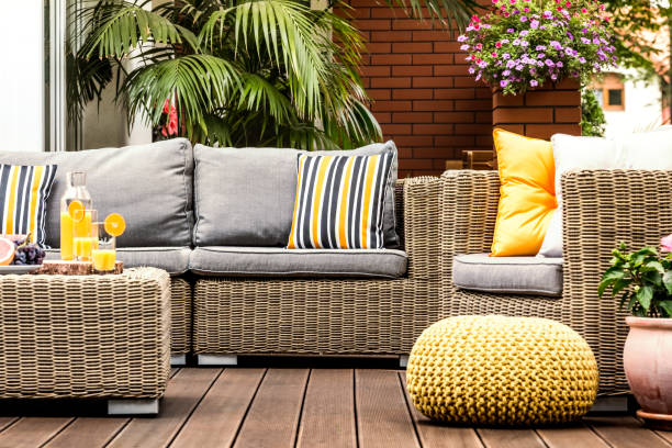 Yellow pouf on wooden terrace Yellow pouf next to rattan armchair on wooden terrace with striped pillows on sofa patio stock pictures, royalty-free photos & images