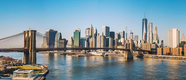 Brooklyn Bridge with sailboats in the East River in front of the Manhattan skyline