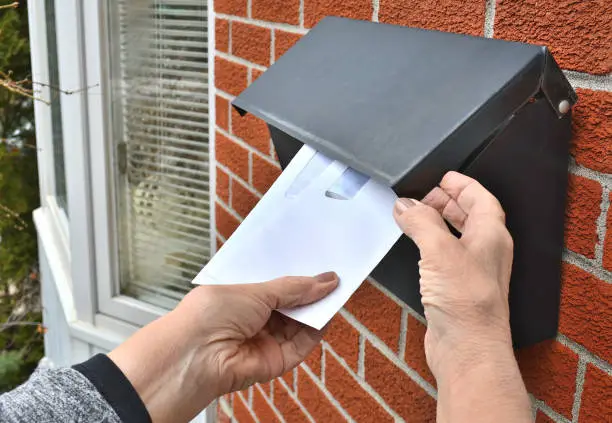 Lifestyle...This is a close up shot of a home owner, taking several envelopes from a front door, residential, letterbox.