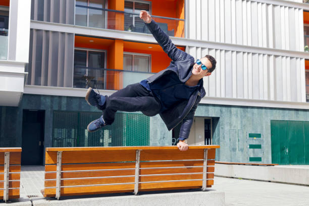 istock Young handsome man jumping a bench in the street. 947062066