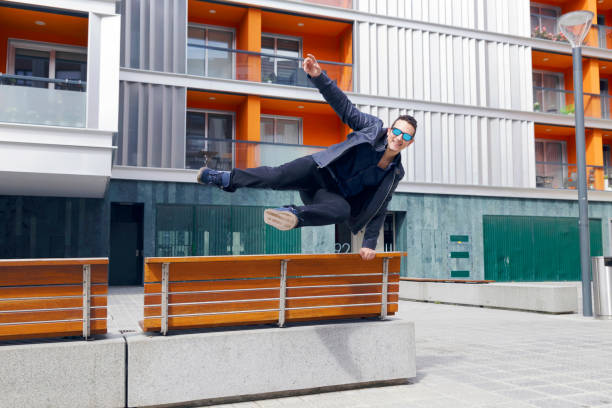 istock Young handsome man jumping a bench in the street. 947062154