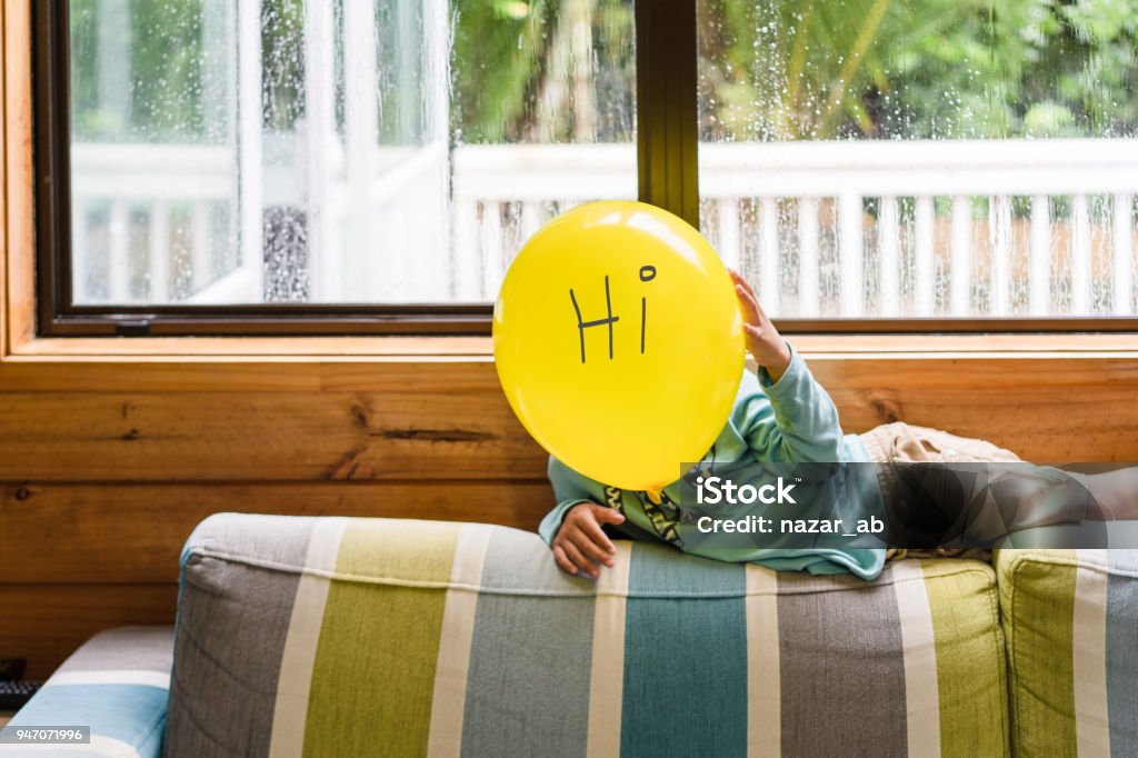 Kid with love face balloon. Kid holding Emoji face balloons and playing at home, in Auckland, New Zealand. Auckland Stock Photo