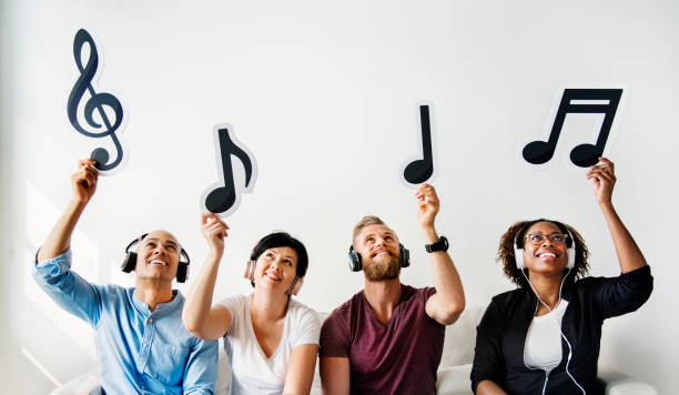 istock People holding musical icons sitting on a sofa 947081882