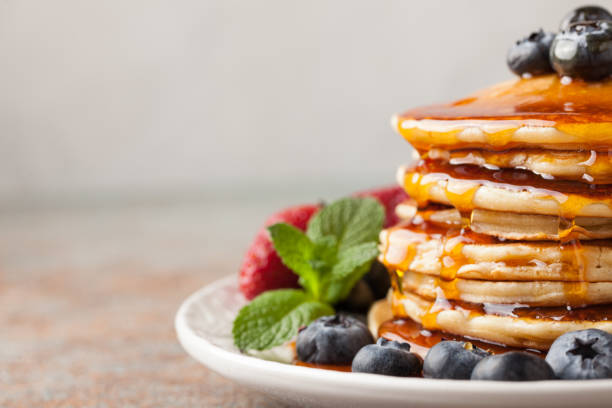 istock Close-up delicious pancakes, with fresh blueberries, strawberries and maple syrup on a light background. With copy space 947088408