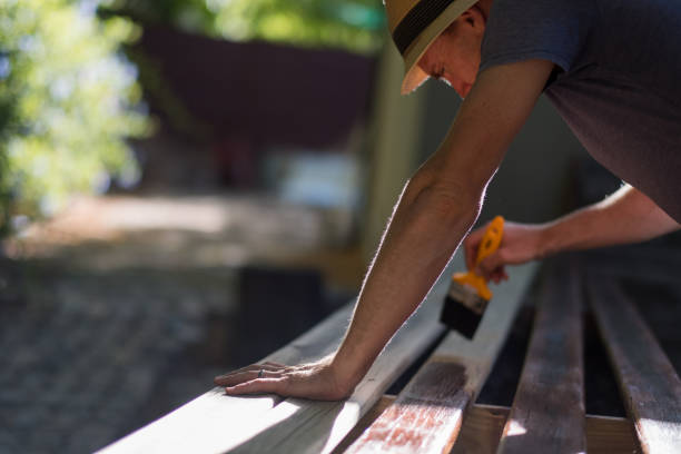 istock Man painting wood outside 947099078