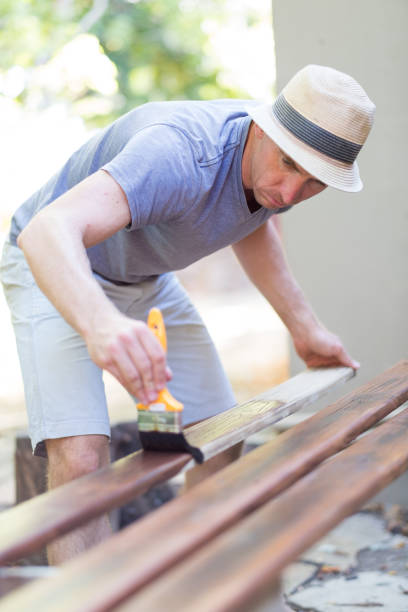 istock Man painting wood outside 947099832