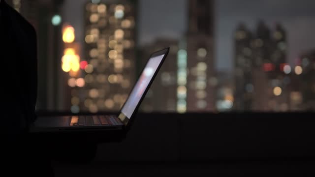 4k resolution Close up man open laptop computer at night with city view