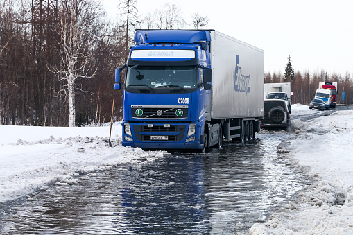 NOVYY URENGOY, RUSSIA - APRIL 23, 2017: Blue semi-trailer truck Volvo FH12 stuck in the puddle..