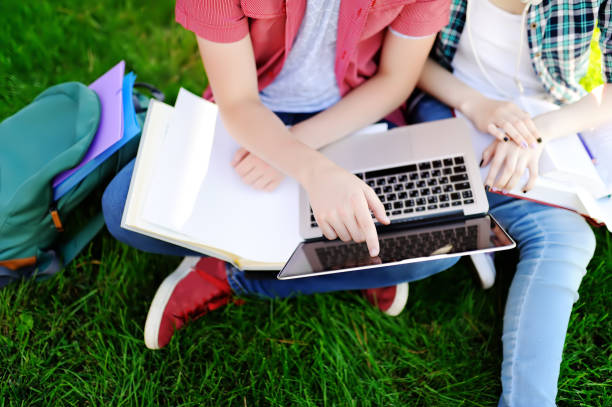 istock Young happy students with laptop, books and notes outdoors 947119148