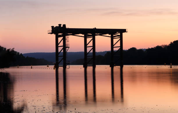 Steel structure silhouetted in water and  against sunset sky Penrith