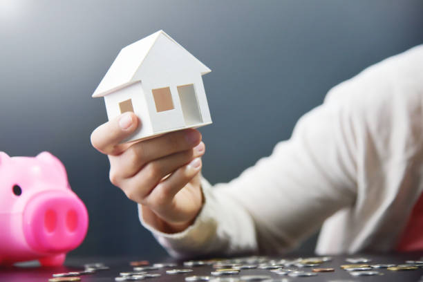 istock Woman hand is holding house model. 947128414