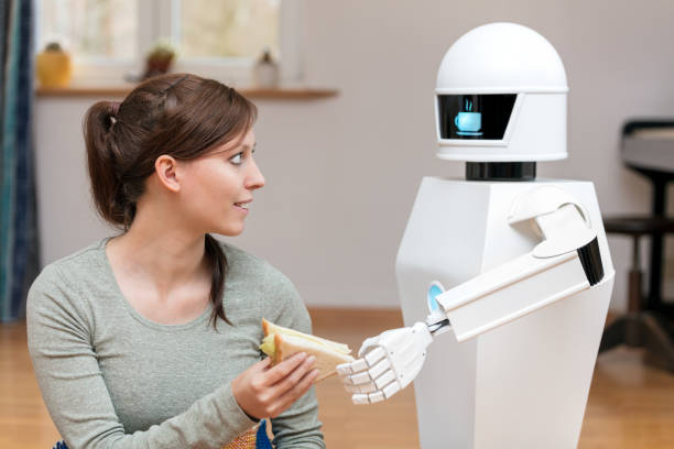サービス ロボットは、ブルネット、かなり女性のリビング ルームでサンドイッチを与えている、家庭用ロボットのディスプレイにコーヒー ブレーク シンボル表示中 - living room learning healthy lifestyle one person ストックフォトと画像