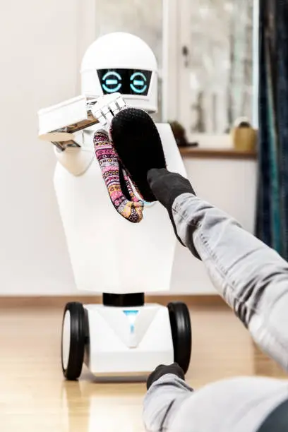 woman is waiting for her slippers, brought by a household service roboter