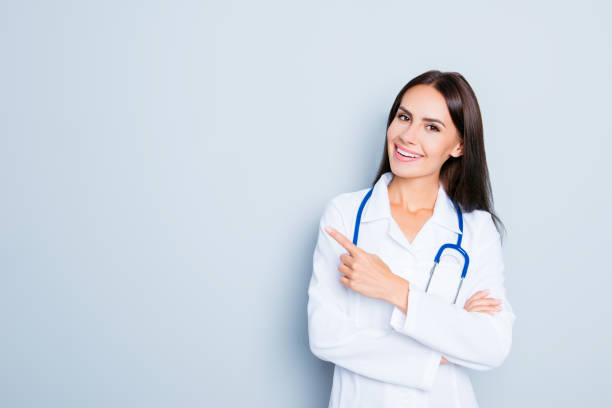 istock Friendly smiling young female doctor pointing with finger 947137172