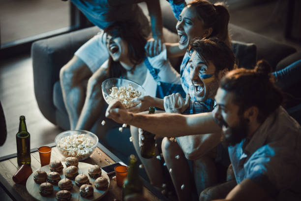 istock Group of ecstatic fans having fun while watching a game on TV at home. 947141292